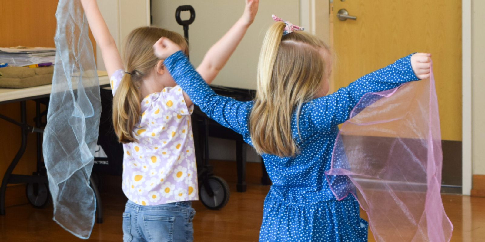 Two students imitating wind with scarves